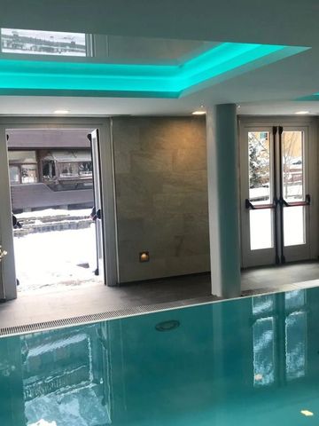 Moderner Innenpool mit Deckenelementen und Winterlandschaft im Hintergrund