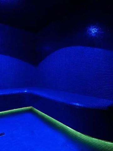 Dunkles Dampfbad mit blauer Beleuchtung und Mosaikwänden