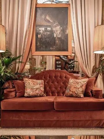 Elegante Lounge mit Samtsofa zwischen zwei Stehlampen im Grand Hotel et de Milan