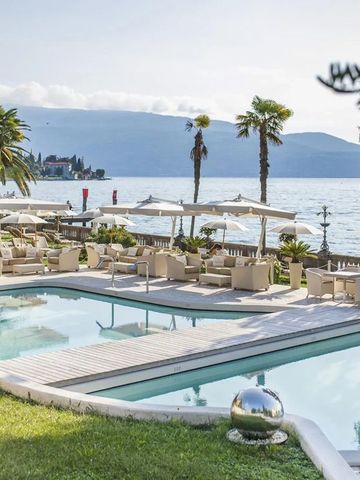 Eleganter Außenpool mit Sonnenschirmen und Seeblick umgeben von Palmen