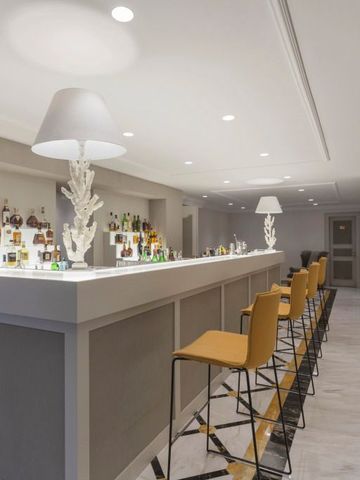 Moderne Hotelbar mit stilvollen Barhockern und beleuchteten Regalen