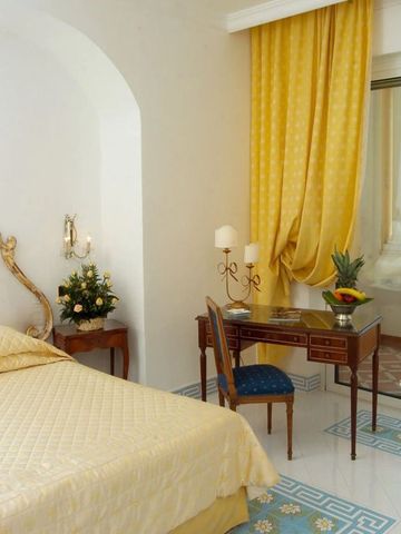 Elegantes Hotelzimmer mit gelben Vorhängen und antikem Schreibtisch