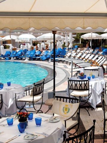 Elegante Poollandschaft mit Sonnenterrasse und gedeckten Tischen im Freien