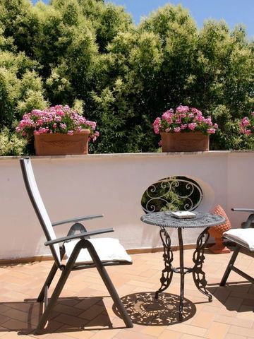 Privater Balkon mit gemütlichen Stühlen und blühenden Pflanzen im Hintergrund