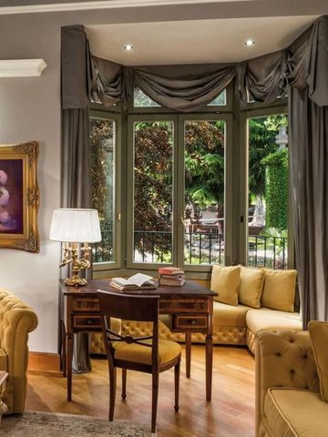 Elegantes Wohnzimmer mit großen Fenstern und antikem Mobiliar.