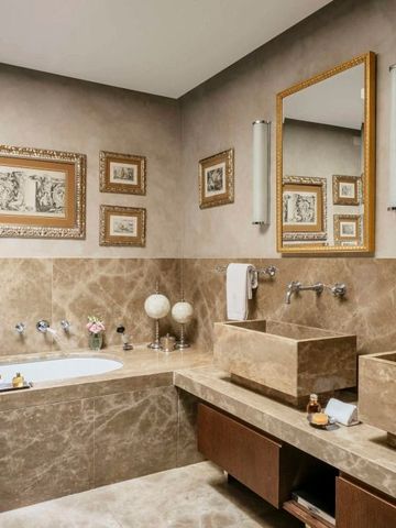 Modernes Badezimmer mit Marmoroberflächen und Kunstwerken an der Wand.