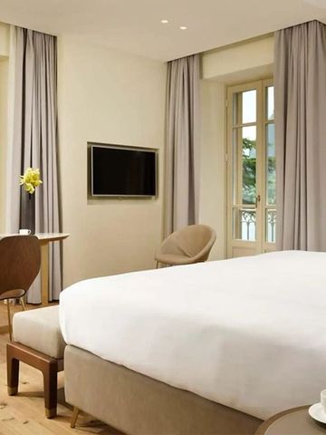 Elegantes Hotelzimmer mit großem Bett, Schreibtisch und Blick auf die umliegende Natur.