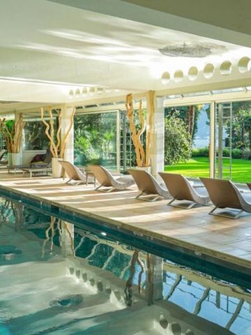 Innenpool mit Liegestühlen und großem Fensterblick ins Grüne