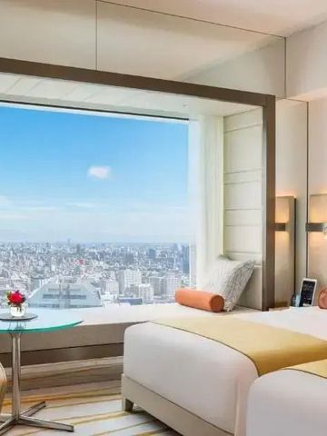 Hotelzimmer mit zwei Betten und beeindruckendem Stadtblick durch ein großes Fenster.