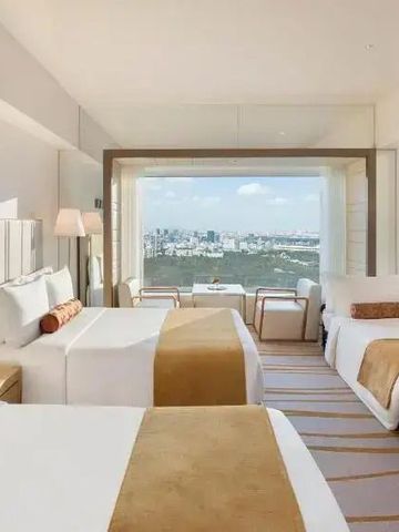 Modernes Zimmer mit drei Betten und weitem Blick auf die Stadtlandschaft.