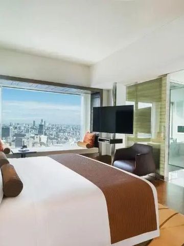 Zimmer mit Kingsize-Bett und großem Fenster mit Aussicht auf Tokio.