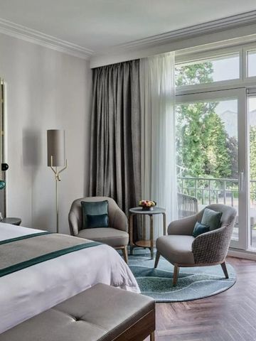 Geräumiges Hotelzimmer mit Balkon und Blick ins Grüne.