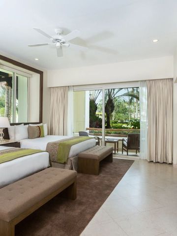 Zimmer mit großen Fenstern und Blick auf Garten und Terrasse.