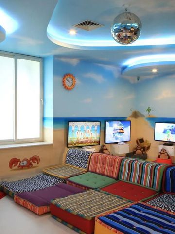 Kinderbereich mit bunten Kissen und Bildschirmen für Unterhaltung