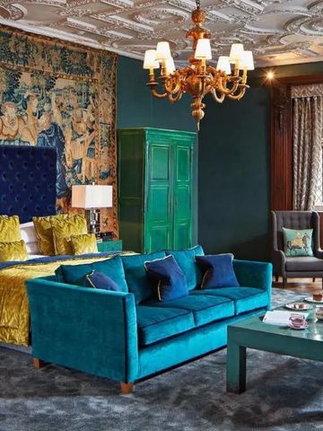 Opulent dekoriertes Schlafzimmer mit Samtsofa und kunstvoller Decke