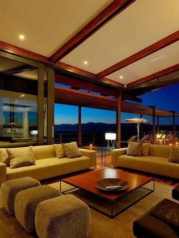 Elegante Lounge mit großer Fensterfront und nächtlicher Aussicht im Grootbos Private Nature Reserve