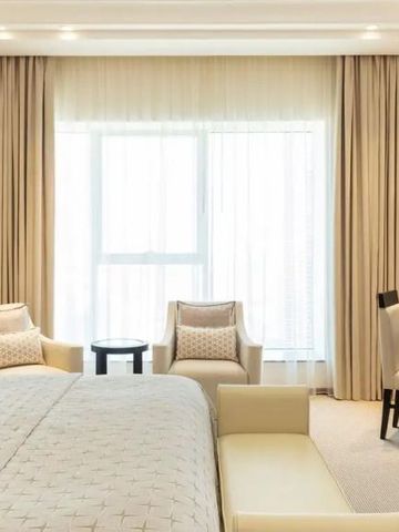 Geräumiges Zimmer mit großen Fenstern und modernen Möbeln in neutralen Tönen