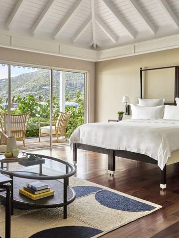 Helles Schlafzimmer mit großem Bett und Blick auf Garten durch Glastüren