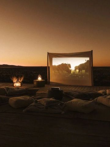 Outdoor-Kino bei Sonnenuntergang mit gemütlichen Sitzgelegenheiten in der Natur