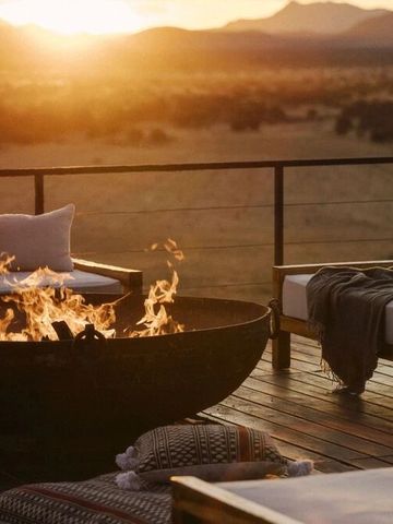 Gemütlicher Lounge-Bereich mit Feuerstelle und Aussicht auf die Berglandschaft bei Sonnenuntergang