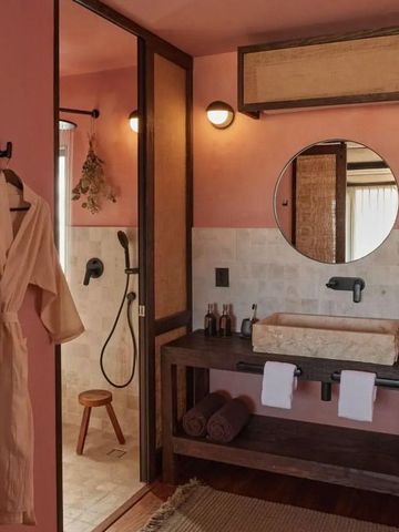 Elegantes Badezimmer mit rosafarbenen Wänden und Rundspiegel