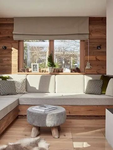 Gemütliche Sitzecke mit Holzwänden und großem Fenster in einem Hotelzimmer