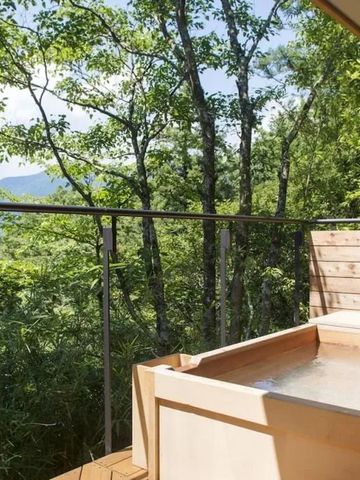 Holzbalkon mit privatem Onsen, umgeben von grüner Natur