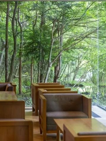 Sitzecke mit Panoramafenster und Ausblick auf dichten Wald