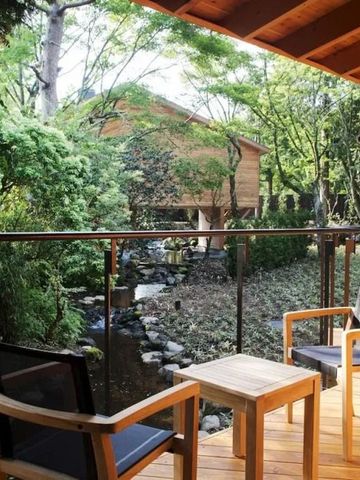 Terrasse mit Sitzmöbeln und Ausblick auf einen kleinen Bach und Bäume