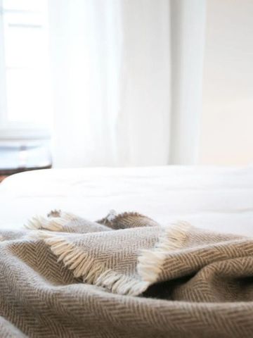 Gemütliches Hotelzimmer mit Tagesdecke und Fenster im Hintergrund