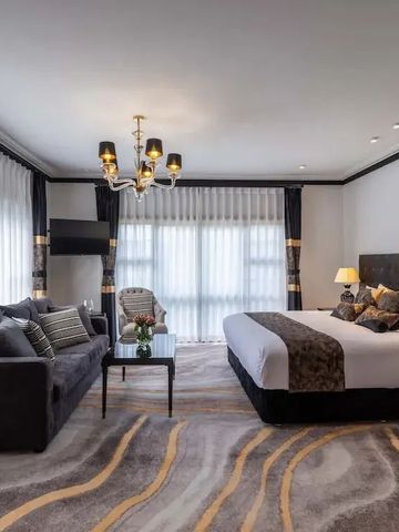 Hotelzimmer mit bequemer Sitzecke und großem Bett in neutralen Tönen