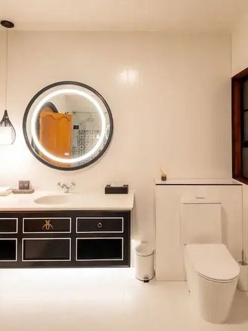 Helles Badezimmer mit eleganten weißen Flächen und Rundspiegel.