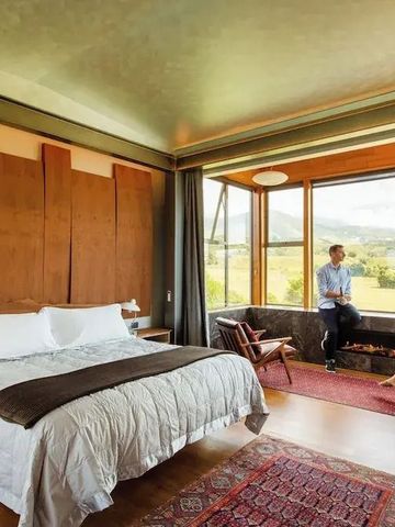 Gemütliches Schlafzimmer mit großen Fenstern und Ausblick auf die Natur