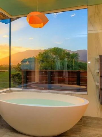 Freistehende Badewanne mit Aussicht auf Sonnenuntergang über den Bergen