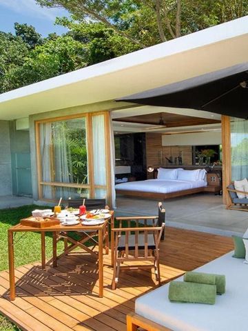 Moderne Villa mit Terrasse, Sonnenliegen und Frühstückstisch im Grünen