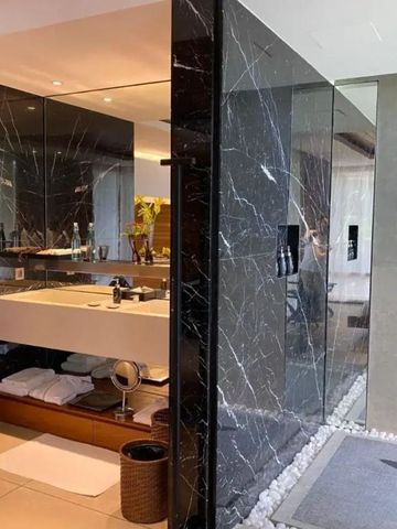 Modernes Badezimmer mit Marmorwänden und durchsichtiger Duschabtrennung.