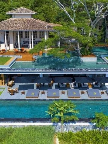 Luftaufnahme einer Villa mit Infinity-Pool und Liegestühlen.