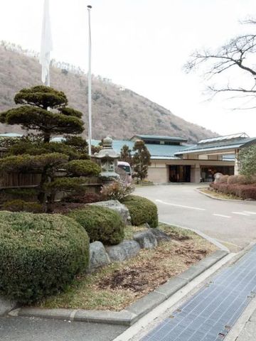 Eingang des Hotels Hatsuhana mit gepflegtem Vorgarten und Gebirgshintergrund.