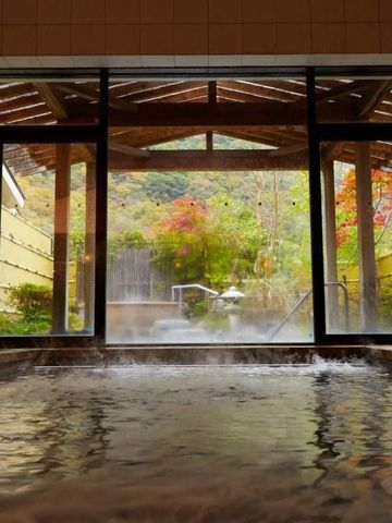 Innenansicht eines Onsen mit Blick auf bunten Garten und Holzpergola.