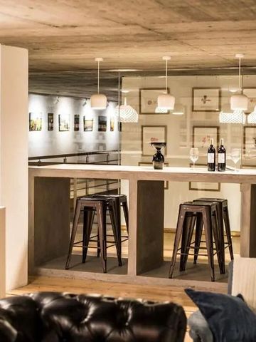 Gemütliche Bar mit hohen Tischen und Hockern aus Holz und Ledersofas