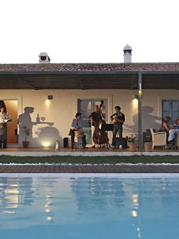 Terrasse mit Pool und Gästen bei Live-Musik in Abendatmosphäre