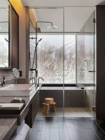 Modernes Badezimmer mit großer Dusche, Badewanne und Blick auf verschneite Landschaft
