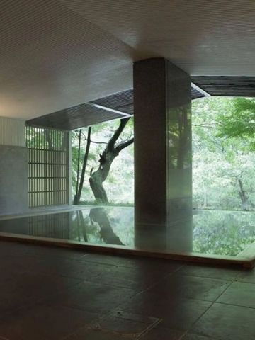 Modernes Indoor-Onsen-Bad mit größzügiger Fensteransicht auf Wald