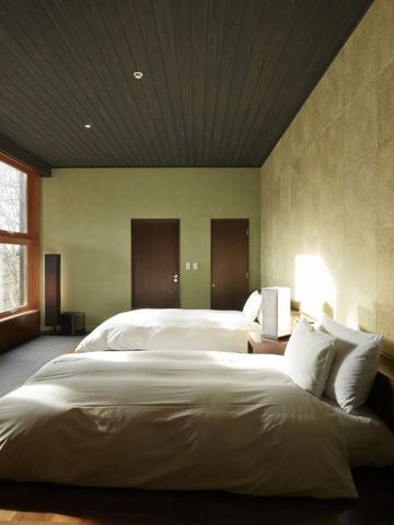 Geräumiges Schlafzimmer mit zwei großen Betten und großen Fenstern