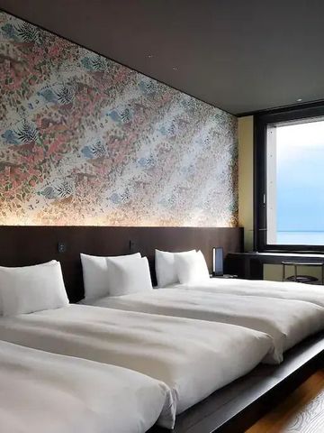 Luxuriöses Hotelzimmer mit drei Betten und großzügigem Fenster mit Ausblick.