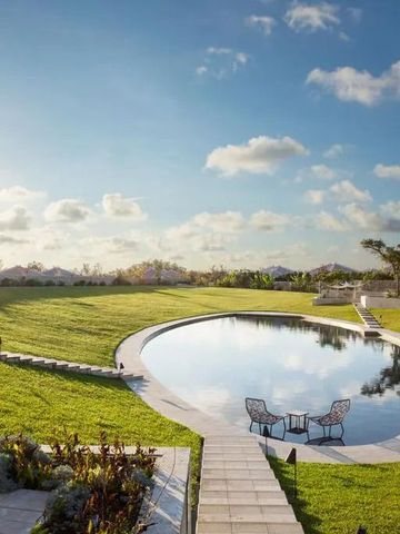 Runder Infinity-Pool inmitten einer grünen Wiese unter blauem Himmel