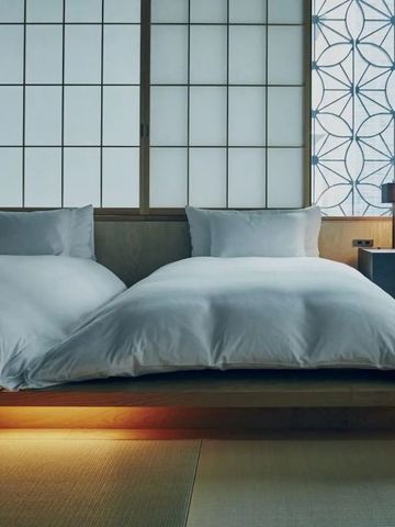 Zwei große Betten in minimalistischer Suite mit Shoji-Wänden im HOSHINOYA Tokyo Hotel