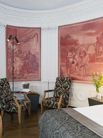 Prächtig dekoriertes Zimmer mit klassischen Wandmalereien und eleganten Sesseln