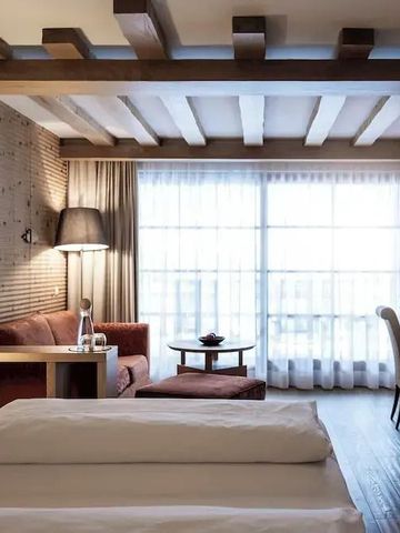 Helles Zimmer mit freiliegenden Balken, großem Fenster und stilvollen Möbeln