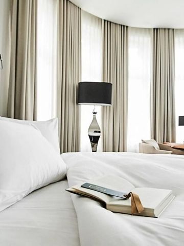 Helles Hotelzimmer mit großen Fenstern und einem Arbeitsbereich.